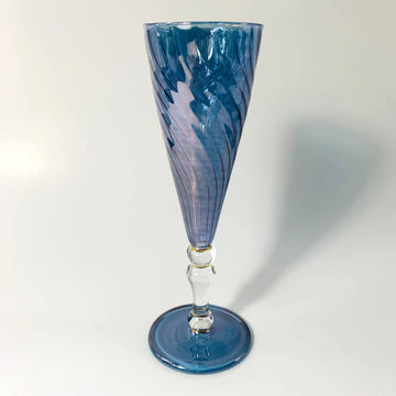 Handblown blue glass champagne flute with contrasting clear stem. Swirled glass motif for main part. Fine gold detail around parts of stem.