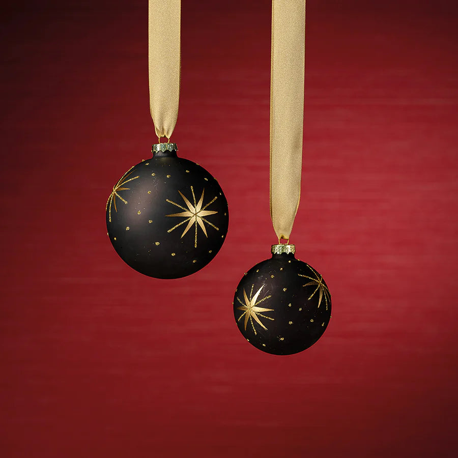 Gold and Black Star Design Ornament 2 seizes behind a  red background hanging by a golden ribbon 