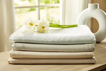 Stack of Legna Dahlia sheets with tulips laid on top in sunny room