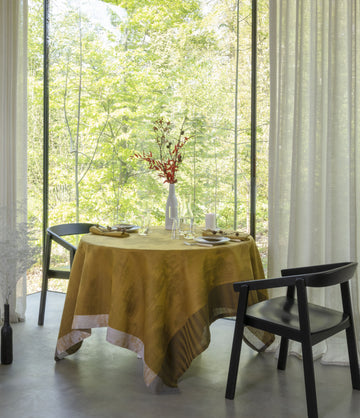 Souveraine Gold Square tablecloth on a round table with table setting 